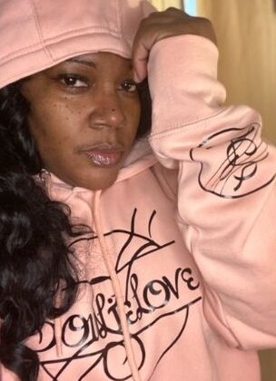 A woman wearing a pink SoulieLove Collections hoodie